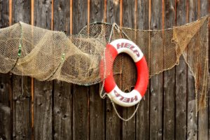 Life preserver and fishing net hanging on a fence